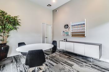 A room with a white table and chairs and a plant.